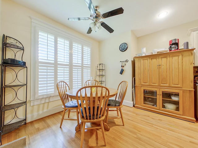 dining space with baseboards, light wood-style flooring, and a ceiling fan