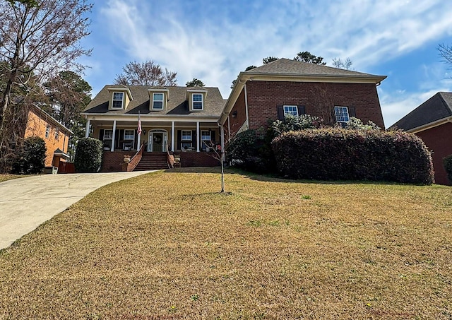 view of front of property with brick siding, covered porch, concrete driveway, and a front lawn