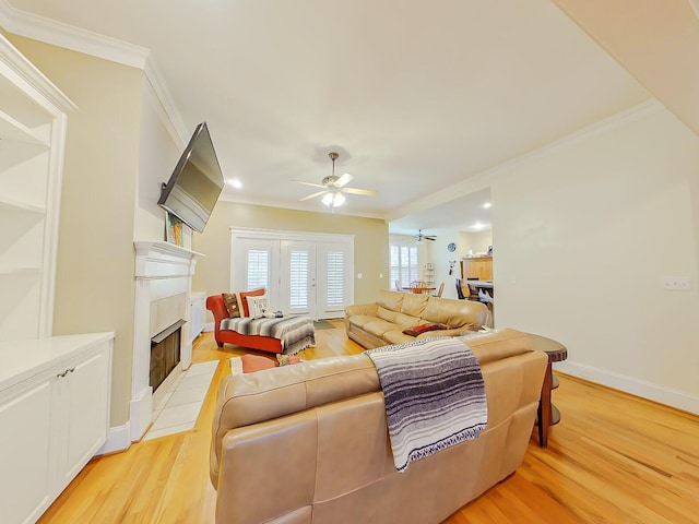 living area featuring a fireplace with flush hearth, ornamental molding, a ceiling fan, light wood-style floors, and baseboards