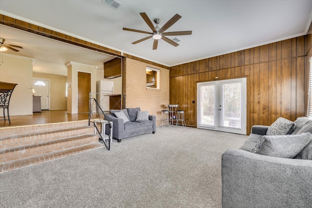3414 Forest Estates Dr, Augusta, GA 30909 - living room featuring ceiling fan, ornamental molding, french doors, wood walls, and carpet floors