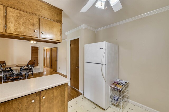 3414 Forest Estates Dr, Augusta, GA 30909 - kitchen with freestanding refrigerator, brown cabinetry, a ceiling fan, ornamental molding, and light countertops