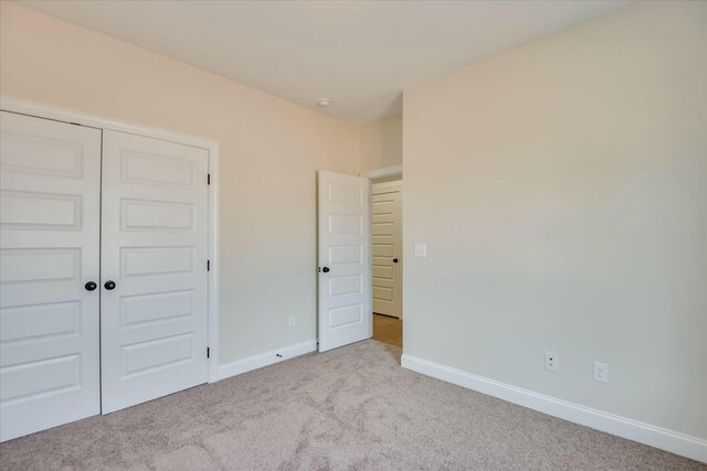unfurnished bedroom featuring baseboards, a closet, and carpet flooring