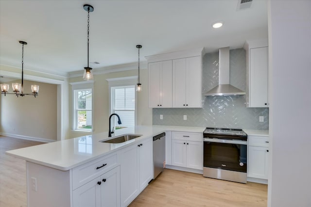 kitchen featuring a sink, stainless steel appliances, decorative backsplash, wall chimney exhaust hood, and light countertops