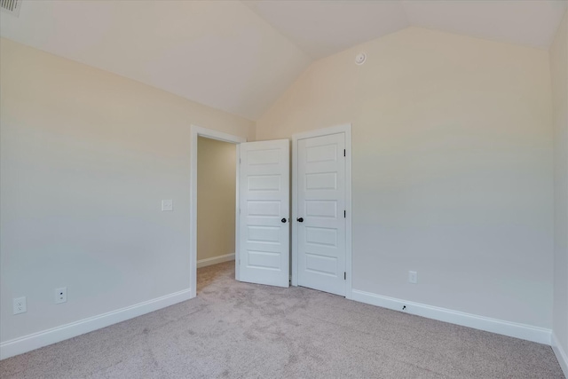 unfurnished bedroom with carpet flooring, lofted ceiling, and baseboards