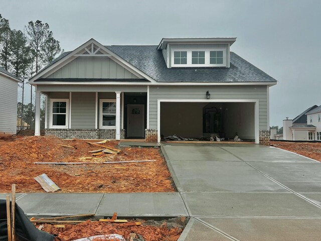 craftsman-style home featuring a garage, covered porch, brick siding, concrete driveway, and board and batten siding