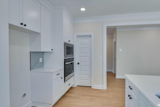 kitchen with appliances with stainless steel finishes, light wood-type flooring, light countertops, and white cabinets