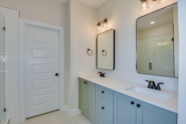 bathroom with a stall shower, double vanity, a sink, and baseboards