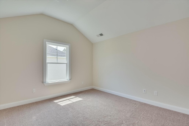 carpeted spare room with visible vents, vaulted ceiling, and baseboards
