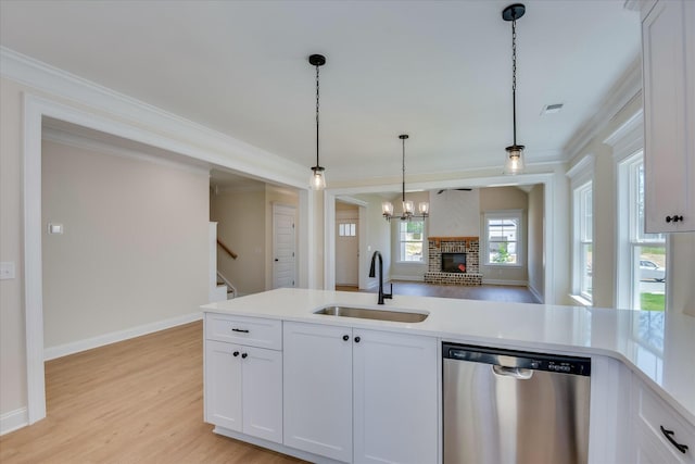 kitchen featuring stainless steel dishwasher, crown molding, a sink, light countertops, and decorative light fixtures