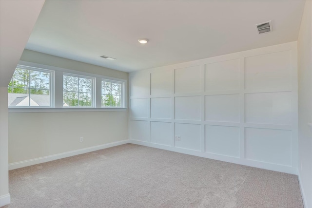 carpeted spare room with a decorative wall, visible vents, and baseboards