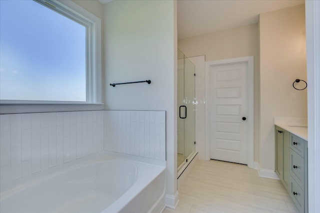 bathroom with a bath, baseboards, vanity, and a stall shower