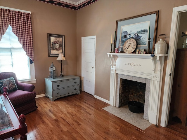 sitting room featuring a tile fireplace, ornamental molding, and light wood-type flooring