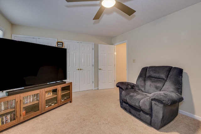 sitting room with carpet, a ceiling fan, and baseboards