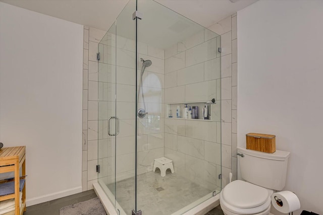 bathroom with a shower stall, toilet, and baseboards