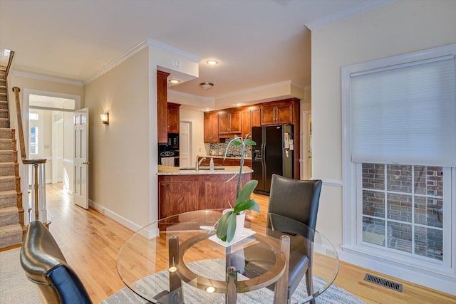 dining space with light wood-style flooring, visible vents, baseboards, ornamental molding, and stairway