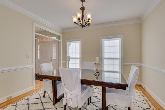 dining space featuring baseboards, a chandelier, wood finished floors, and ornamental molding