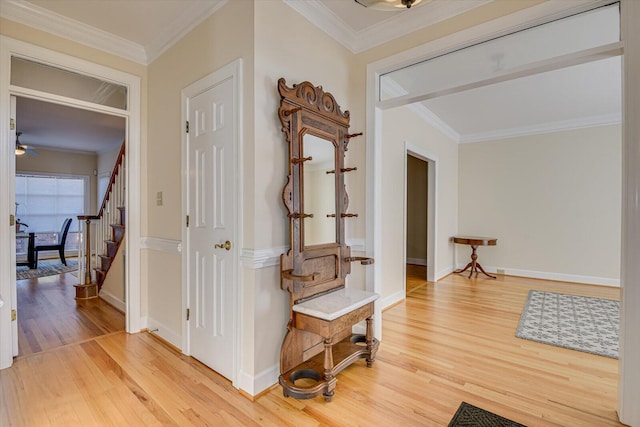 hall featuring light wood-type flooring, baseboards, stairs, and ornamental molding