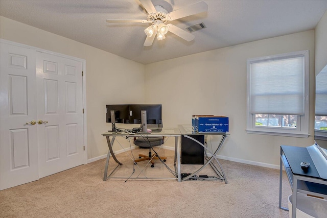 carpeted office space featuring ceiling fan, a textured ceiling, visible vents, and baseboards