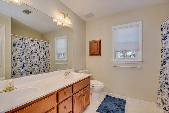 full bathroom with double vanity, tile patterned flooring, a sink, and toilet