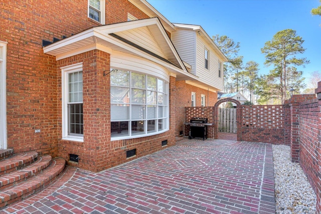 view of side of property with brick siding, crawl space, fence, and a gate