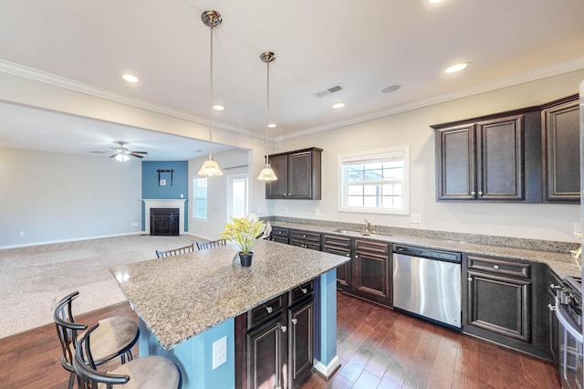 kitchen with a center island, a kitchen bar, stainless steel appliances, sink, and hanging light fixtures