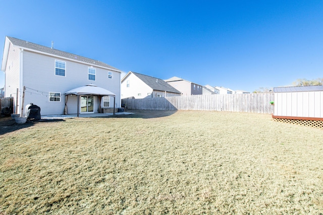 rear view of property featuring a patio area, a lawn, a gazebo, and a storage unit