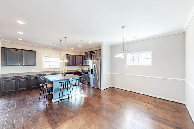 kitchen with stainless steel appliances, decorative light fixtures, dark brown cabinets, a breakfast bar, and a center island