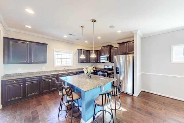 kitchen featuring a center island, decorative light fixtures, stainless steel appliances, sink, and light stone counters