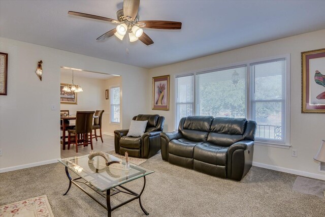 carpeted living room with ceiling fan with notable chandelier