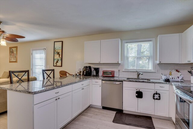 kitchen featuring white cabinetry, sink, light stone countertops, tasteful backsplash, and appliances with stainless steel finishes