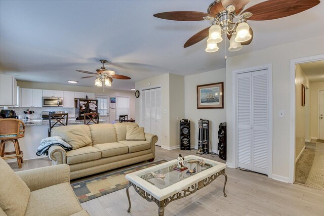 living room featuring ceiling fan and light hardwood / wood-style flooring