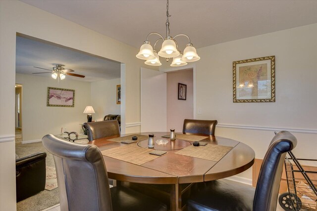 dining space featuring carpet flooring and ceiling fan with notable chandelier