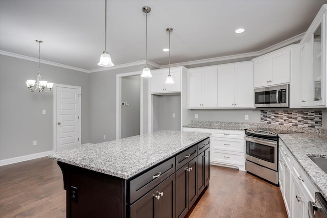 kitchen with appliances with stainless steel finishes, light stone counters, pendant lighting, a chandelier, and a center island