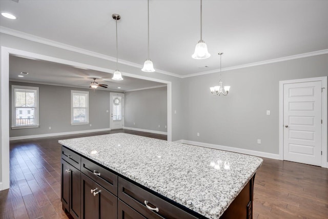 kitchen with a center island, dark hardwood / wood-style flooring, decorative light fixtures, ceiling fan with notable chandelier, and ornamental molding