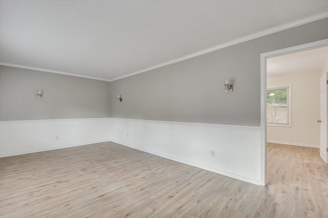 empty room featuring a wainscoted wall, ornamental molding, and wood finished floors