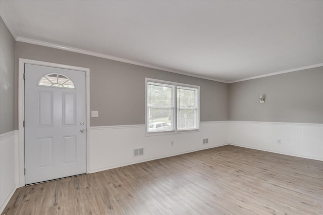 entrance foyer featuring ornamental molding, wainscoting, visible vents, and wood finished floors