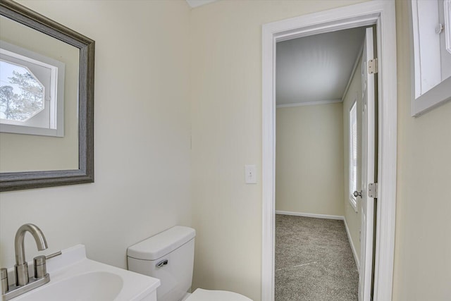 bathroom with ornamental molding, baseboards, a sink, and toilet