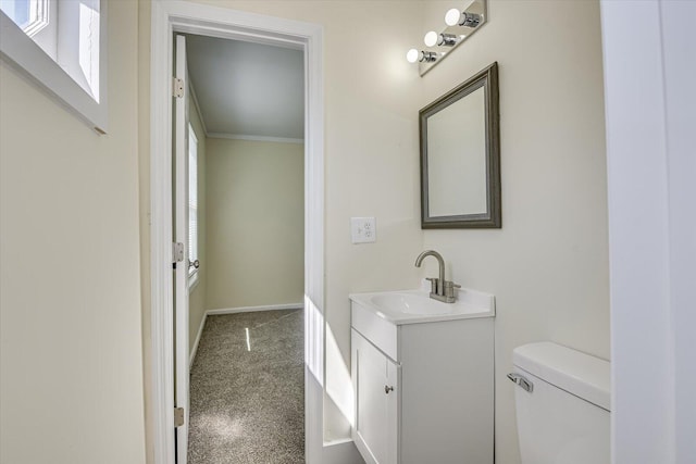 half bath featuring ornamental molding, baseboards, vanity, and toilet