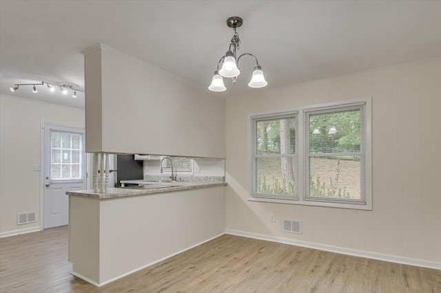 kitchen featuring a peninsula, light wood finished floors, visible vents, and hanging light fixtures