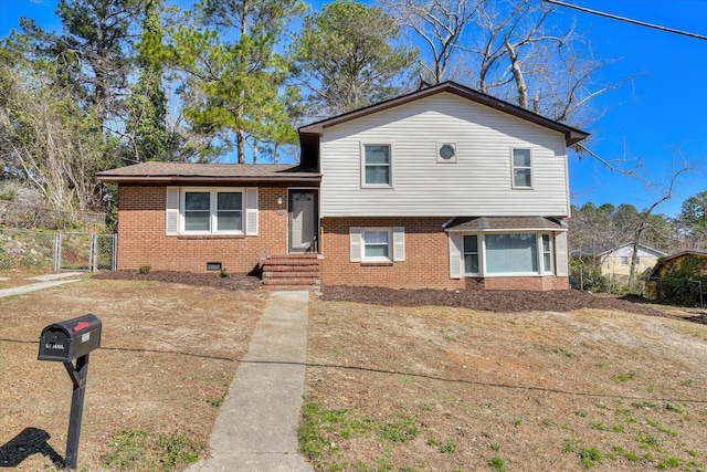 split level home with brick siding, crawl space, fence, and a gate