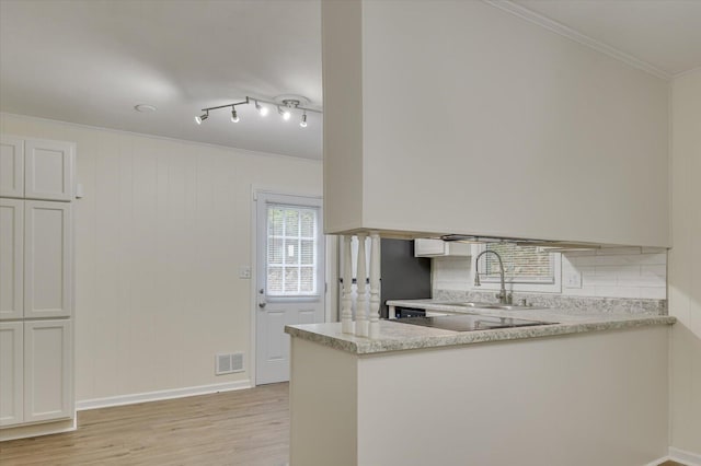 kitchen with visible vents, decorative backsplash, ornamental molding, a sink, and a peninsula