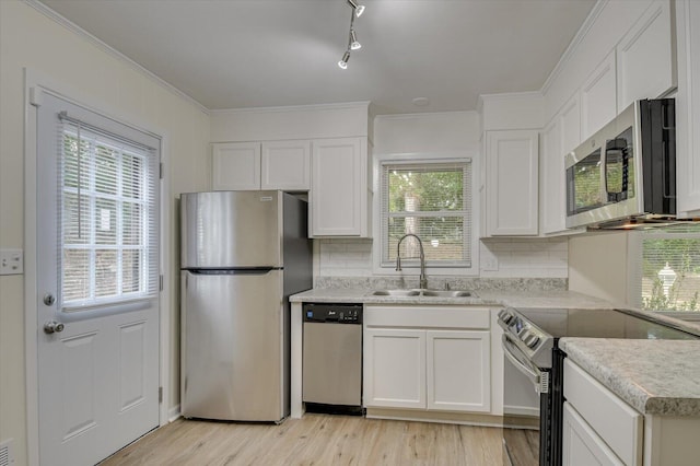 kitchen with light wood finished floors, light countertops, appliances with stainless steel finishes, white cabinets, and a sink