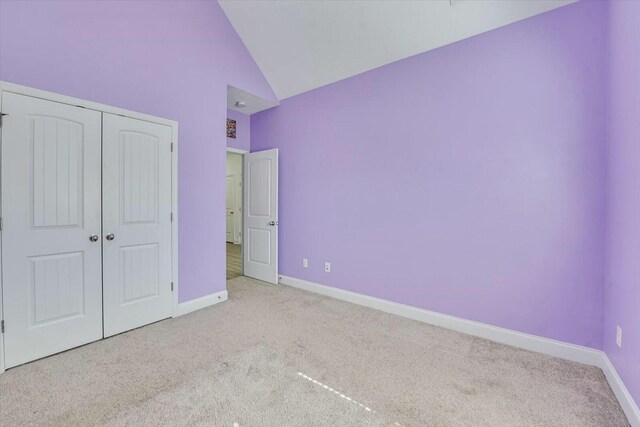 unfurnished bedroom with carpet, baseboards, a closet, and high vaulted ceiling