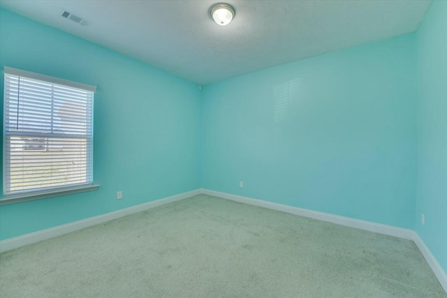 carpeted spare room with visible vents and baseboards