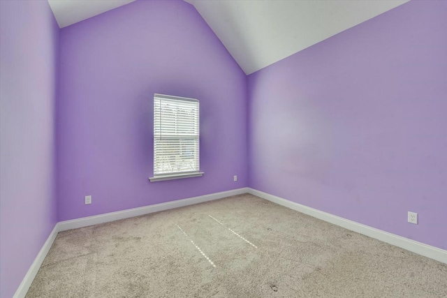 carpeted spare room featuring baseboards and lofted ceiling