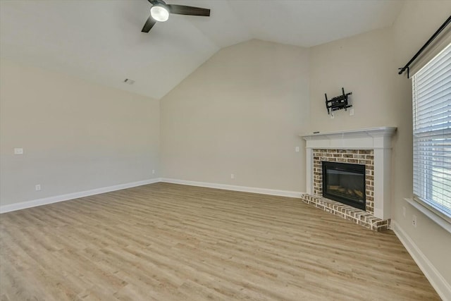 unfurnished living room with baseboards, ceiling fan, vaulted ceiling, a fireplace, and wood finished floors