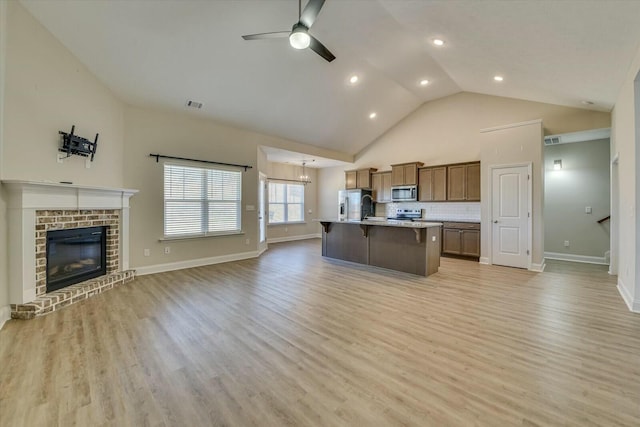 kitchen with an island with sink, light countertops, appliances with stainless steel finishes, a kitchen breakfast bar, and open floor plan