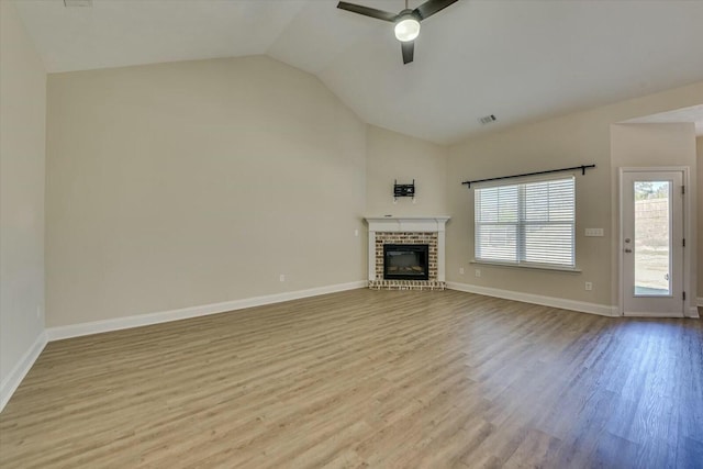 unfurnished living room featuring visible vents, a brick fireplace, ceiling fan, vaulted ceiling, and wood finished floors