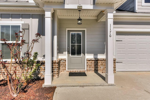 view of exterior entry featuring brick siding, an attached garage, and concrete driveway