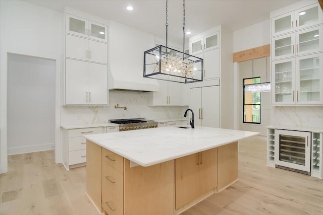 kitchen with wine cooler, white cabinetry, a center island with sink, and stainless steel gas cooktop